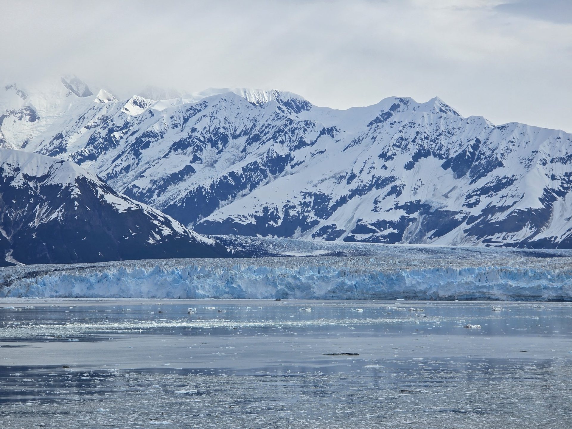 Hubbard Glacier and snow-covered mountains above icy water in Alaska